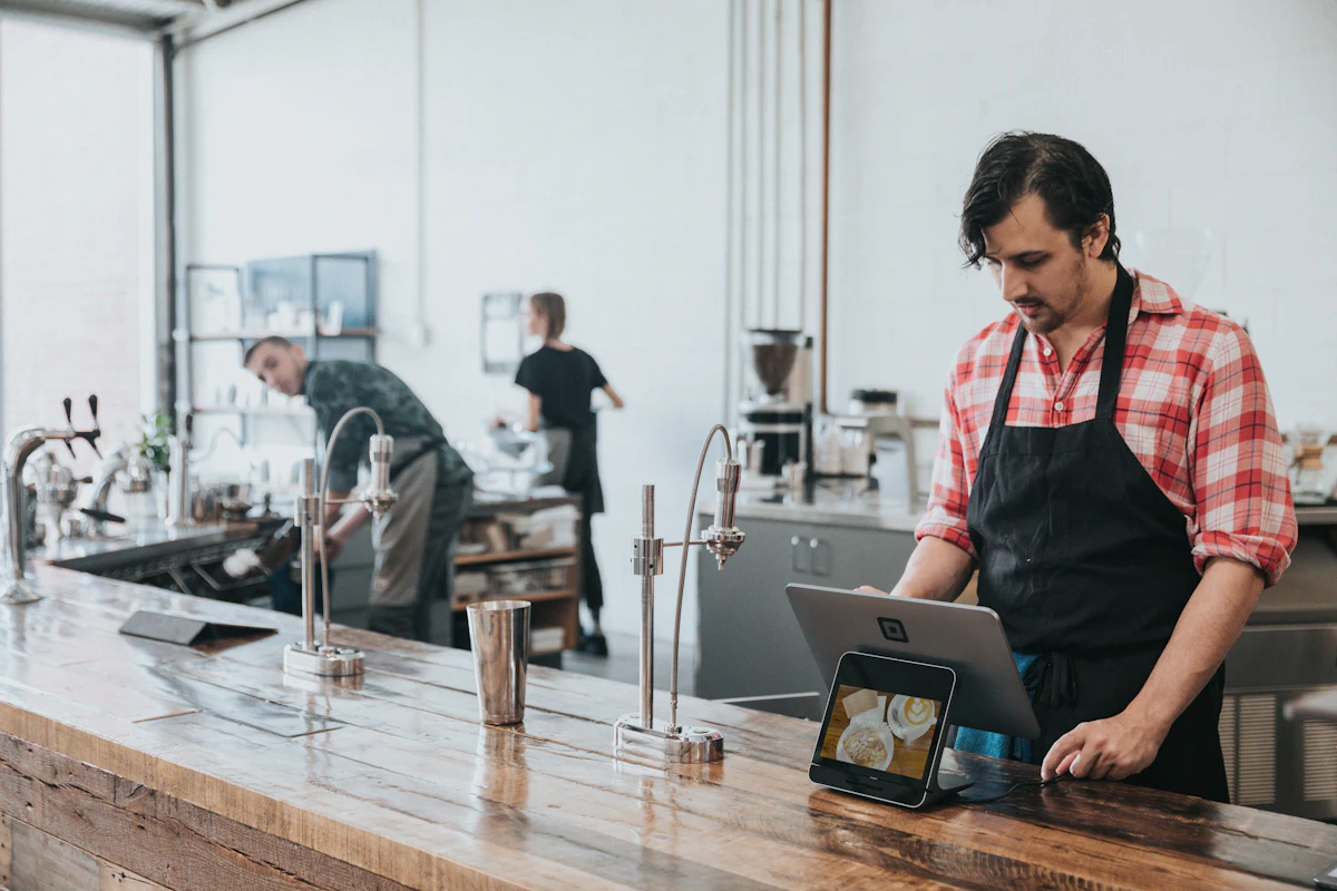A café owner checking the week's rota on a tablet at the counter